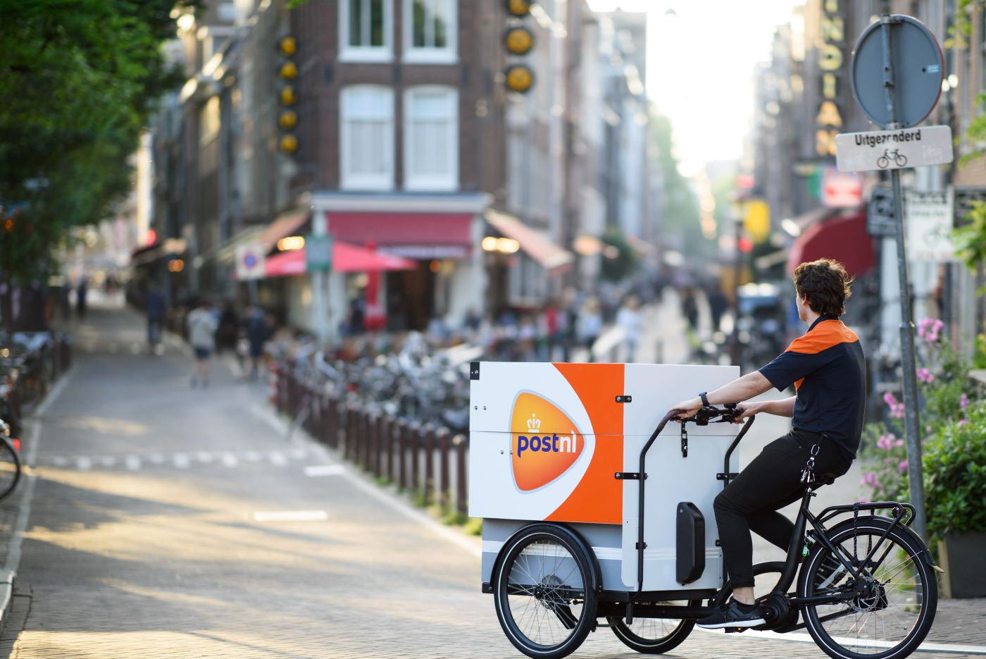 PostNL medewerker op een PostNL fiets die door een straat in Utrecht fietst